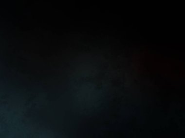 Takım elbiseli ve kravatlı bir adam karanlık bir arka planın önünde duruyor.