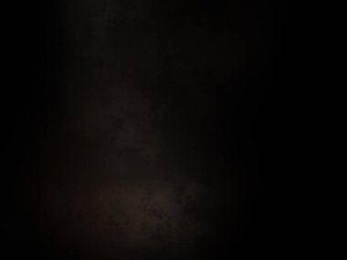 Siyah bir arka planın önünde duran takım elbiseli ve kravatlı bir adam.