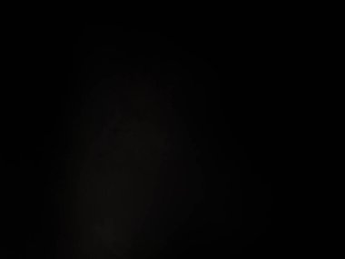 Siyah bir arka planın önünde duran takım elbiseli ve kravatlı bir adam.