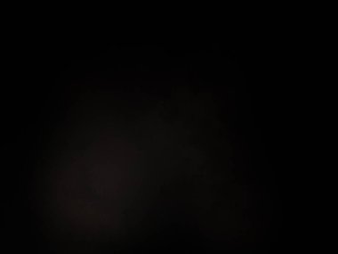 Karanlıkta duran takım elbiseli ve kravatlı bir adam.