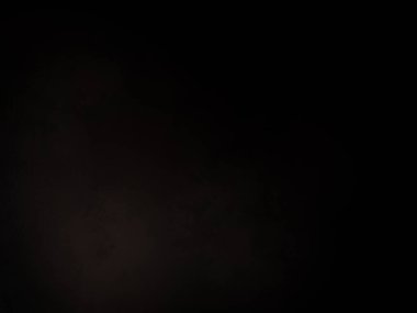 Siyah bir arka planın önünde duran takım elbiseli ve kravatlı bir adam.