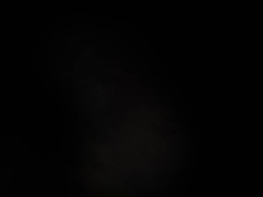 Siyah bir arka planın önünde duran takım elbiseli ve kravatlı bir adam.