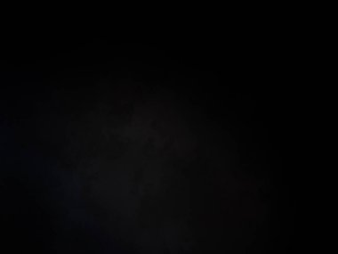 Siyah bir arka planın önünde duran takım elbiseli ve kravatlı bir adam.