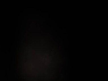 Siyah bir arka planın önünde duran takım elbiseli ve kravatlı bir adam.