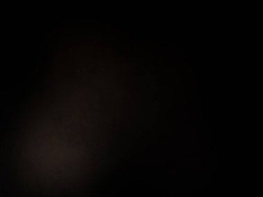 Siyah bir arka planın önünde duran takım elbiseli ve kravatlı bir adam.