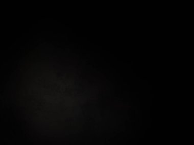 Siyah bir arka planın önünde duran takım elbiseli ve kravatlı bir adam.