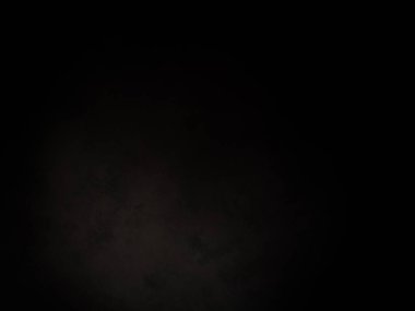 Siyah bir arka planın önünde duran takım elbiseli ve kravatlı bir adam.