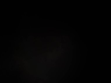 Siyah bir arka planın önünde duran takım elbiseli ve kravatlı bir adam.