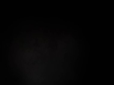 Siyah bir arka planın önünde duran takım elbiseli ve kravatlı bir adam.