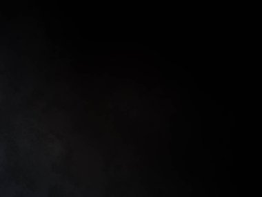 Siyah bir arka planın önünde duran takım elbiseli ve kravatlı bir adam.