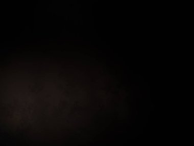 Siyah bir arka planın önünde duran takım elbiseli ve kravatlı bir adam.