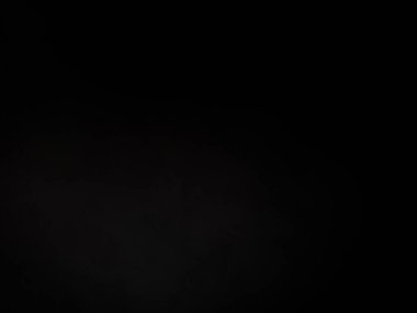 Siyah bir arka planın önünde duran takım elbiseli ve kravatlı bir adam.