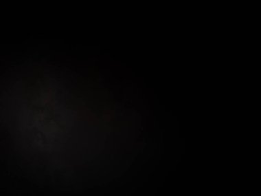 Siyah bir arka planın önünde duran takım elbiseli ve kravatlı bir adam.