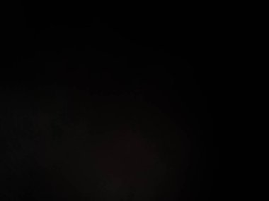 Siyah bir arka planın önünde duran takım elbiseli ve kravatlı bir adam.