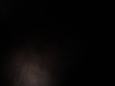 Siyah bir arka planın önünde duran takım elbiseli ve kravatlı bir adam.