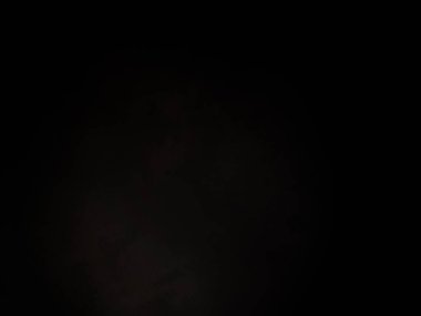 Siyah bir arka planın önünde duran takım elbiseli ve kravatlı bir adam.