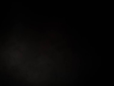 Siyah bir arka planın önünde duran takım elbiseli ve kravatlı bir adam.