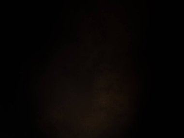 Siyah bir arka planın önünde duran takım elbiseli ve kravatlı bir adam.