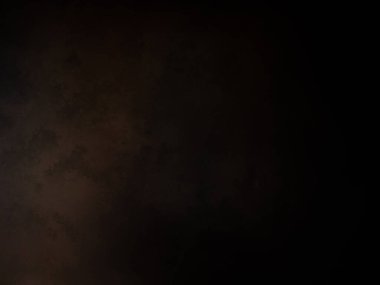 Takım elbiseli ve kravatlı bir adam karanlık bir arka planın önünde duruyor.