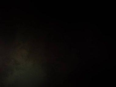 Karanlıkta duran takım elbiseli ve kravatlı bir adam.