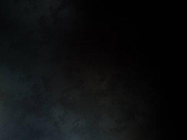 Siyah bir arka planın önünde duran takım elbiseli ve kravatlı bir adam.