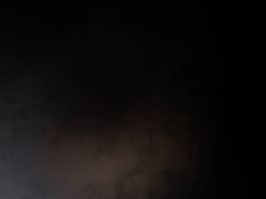 Takım elbiseli ve kravatlı bir adam karanlık bir arka planın önünde duruyor.