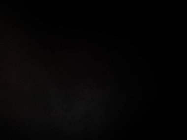 Siyah bir arka planın önünde duran takım elbiseli ve kravatlı bir adam.