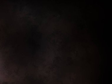 Takım elbiseli ve kravatlı bir adam karanlık bir arka planın önünde duruyor.