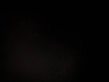 Siyah bir arka planın önünde duran takım elbiseli ve kravatlı bir adam.