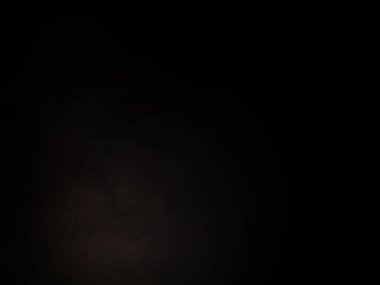 Siyah bir arka planın önünde duran takım elbiseli ve kravatlı bir adam.