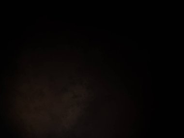 Takım elbiseli ve kravatlı bir adam karanlık bir arka planın önünde duruyor.