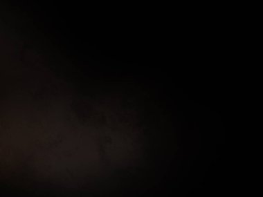 Siyah bir arka planın önünde duran takım elbiseli ve kravatlı bir adam.