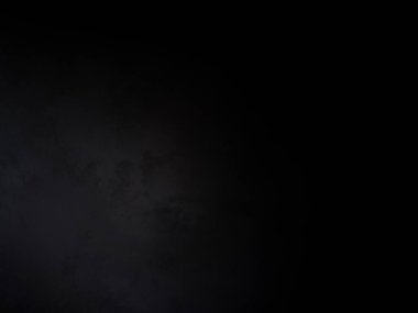 Siyah bir arka planın önünde duran takım elbiseli ve kravatlı bir adam.