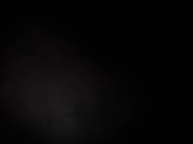 Siyah bir arka planın önünde duran takım elbiseli ve kravatlı bir adam.