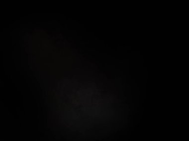 Siyah bir arka planın önünde duran takım elbiseli ve kravatlı bir adam.