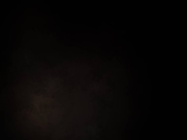 Siyah bir arka planın önünde duran takım elbiseli ve kravatlı bir adam.