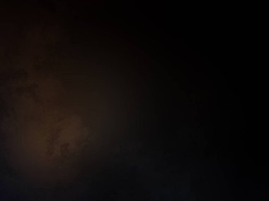 Takım elbiseli ve kravatlı bir adam karanlık bir arka planın önünde duruyor.