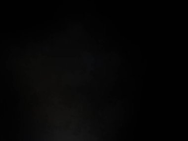 Siyah bir arka planın önünde duran takım elbiseli ve kravatlı bir adam.