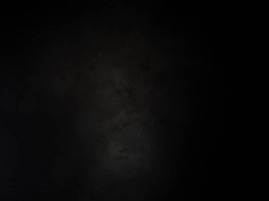 Siyah arka planda duran siyah gömlekli ve kravatlı bir adam.