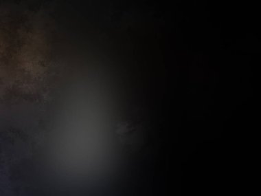 Takım elbiseli ve kravatlı bir adam karanlık bir arka planın önünde duruyor.