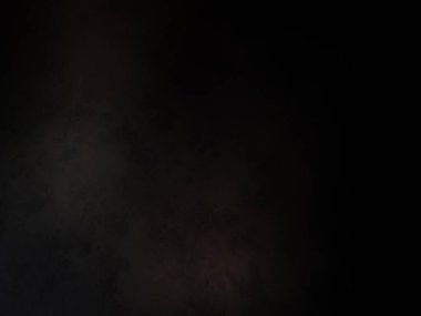 Siyah bir arka planın önünde duran takım elbiseli ve kravatlı bir adam.