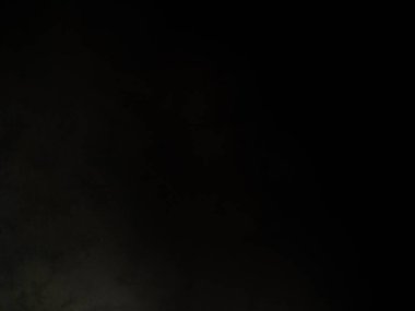 Karanlık bir yüzeyde kaykay süren bir adam.