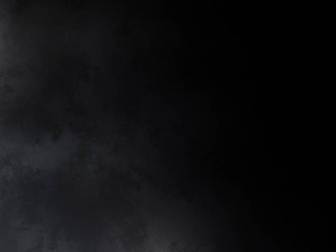 Takım elbiseli ve kravatlı bir adam karanlık bir arka planın önünde duruyor.