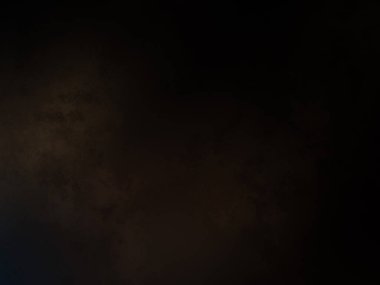 Takım elbiseli ve kravatlı bir adam karanlık bir arka planın önünde duruyor.