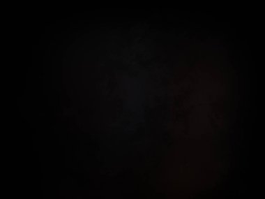 Siyah bir arka planın önünde duran takım elbiseli ve kravatlı bir adam.