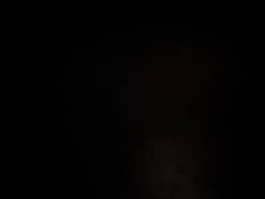 Siyah bir arka planın önünde duran takım elbiseli ve kravatlı bir adam.