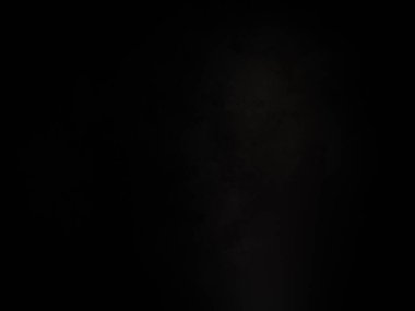 Karanlıkta duran takım elbiseli ve kravatlı bir adam.