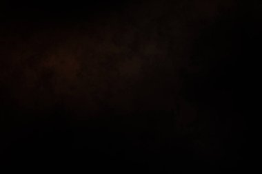 Siyah bir arka planın önünde duran takım elbiseli ve kravatlı bir adam.