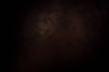 Takım elbiseli ve kravatlı bir adam karanlık bir arka planın önünde duruyor.