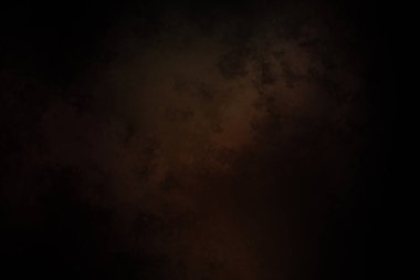 Takım elbiseli ve kravatlı bir adam karanlık bir arka planın önünde duruyor.